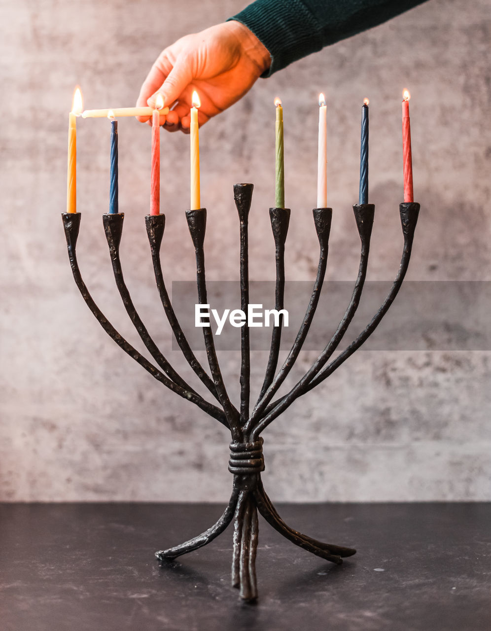 Cropped image of a hand lighting candles on menorah for hanukkah.