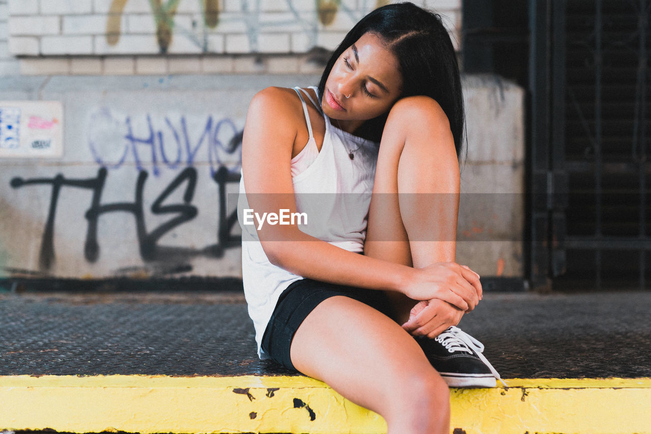 Young woman sitting on sidewalk