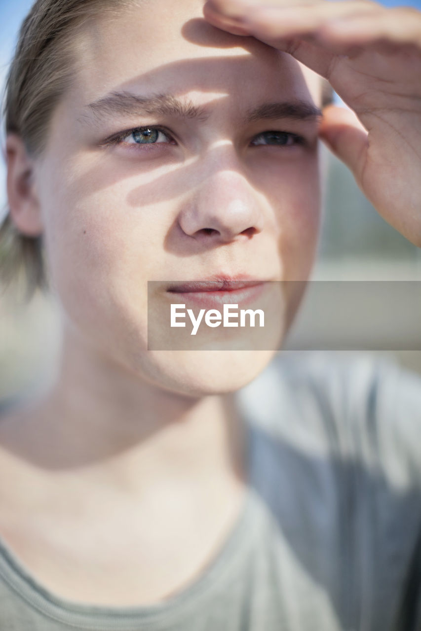 Close-up of young man shielding his eyes from sun