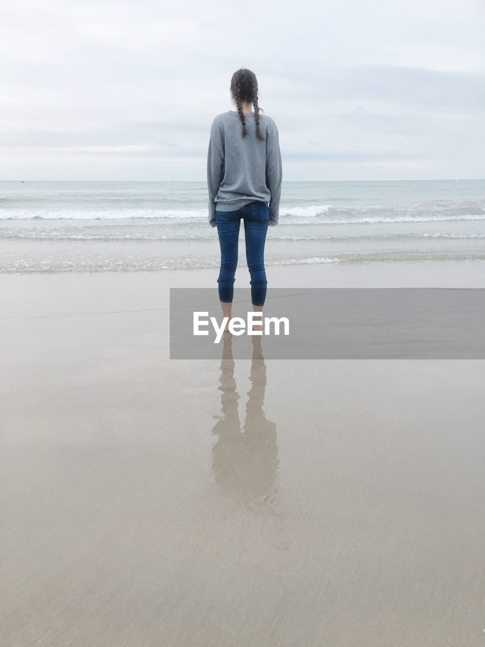 Rear view of man standing on beach against sky