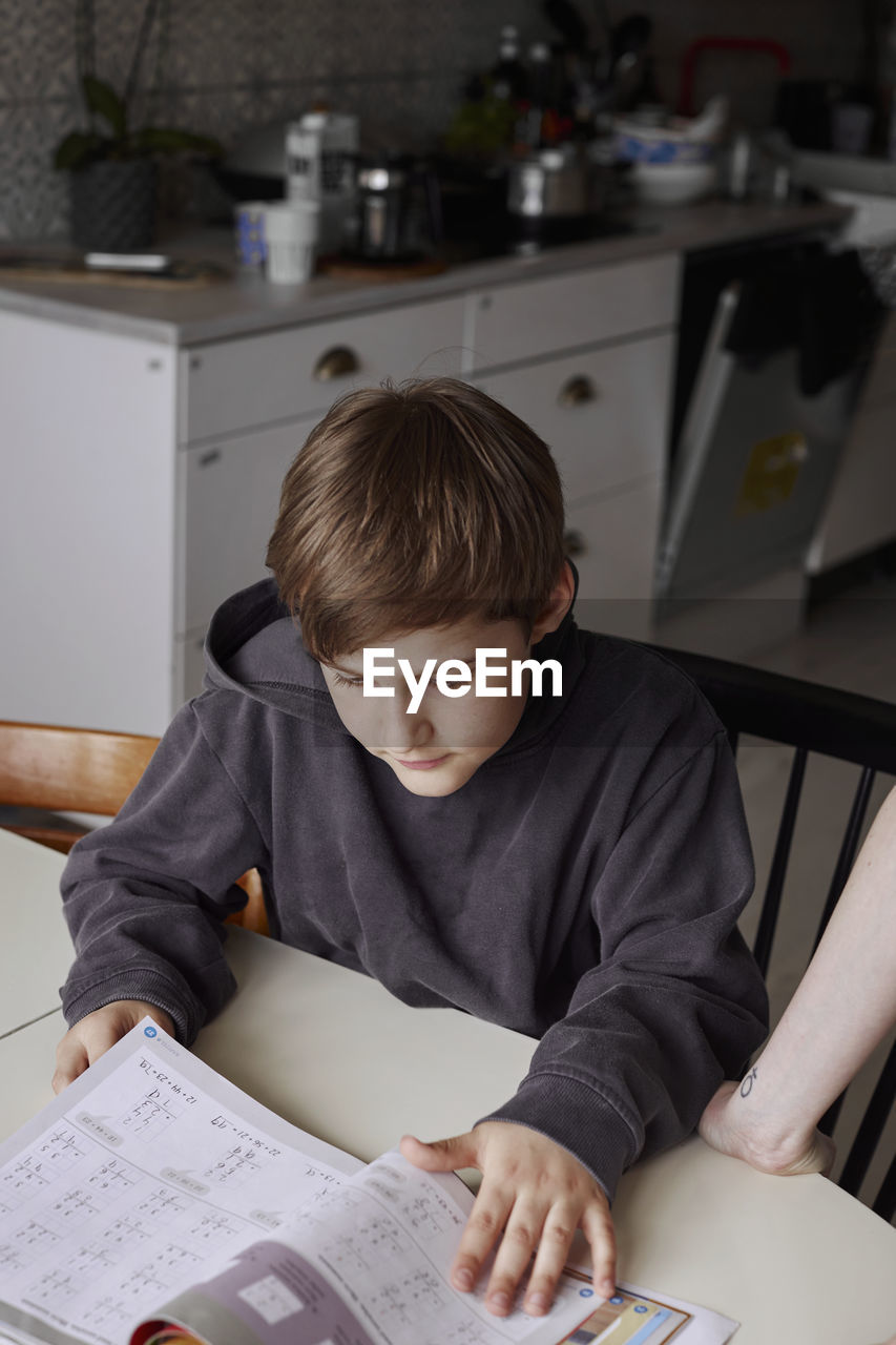 Boy sitting at table and doing homework