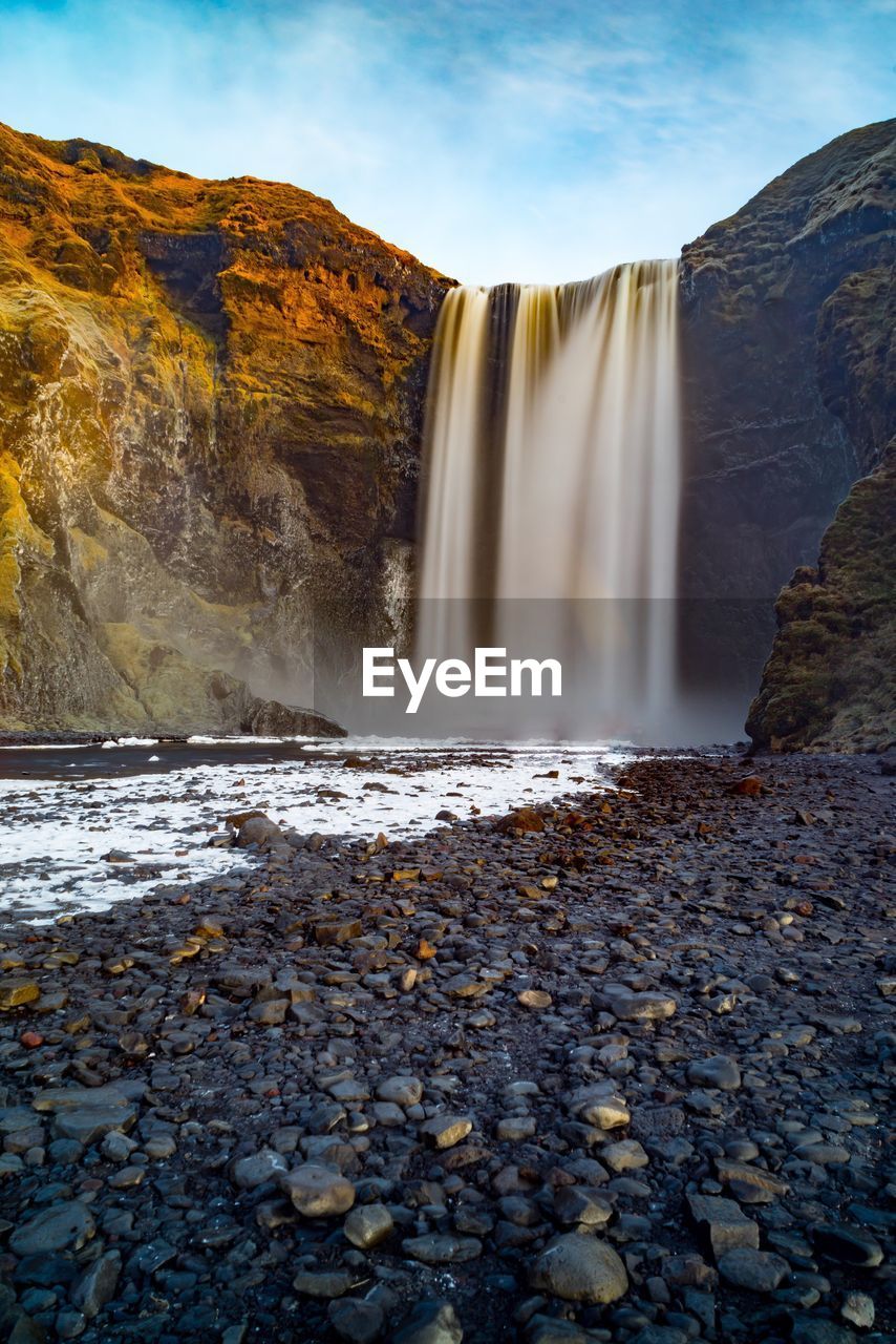 SCENIC VIEW OF WATERFALL AGAINST SKY