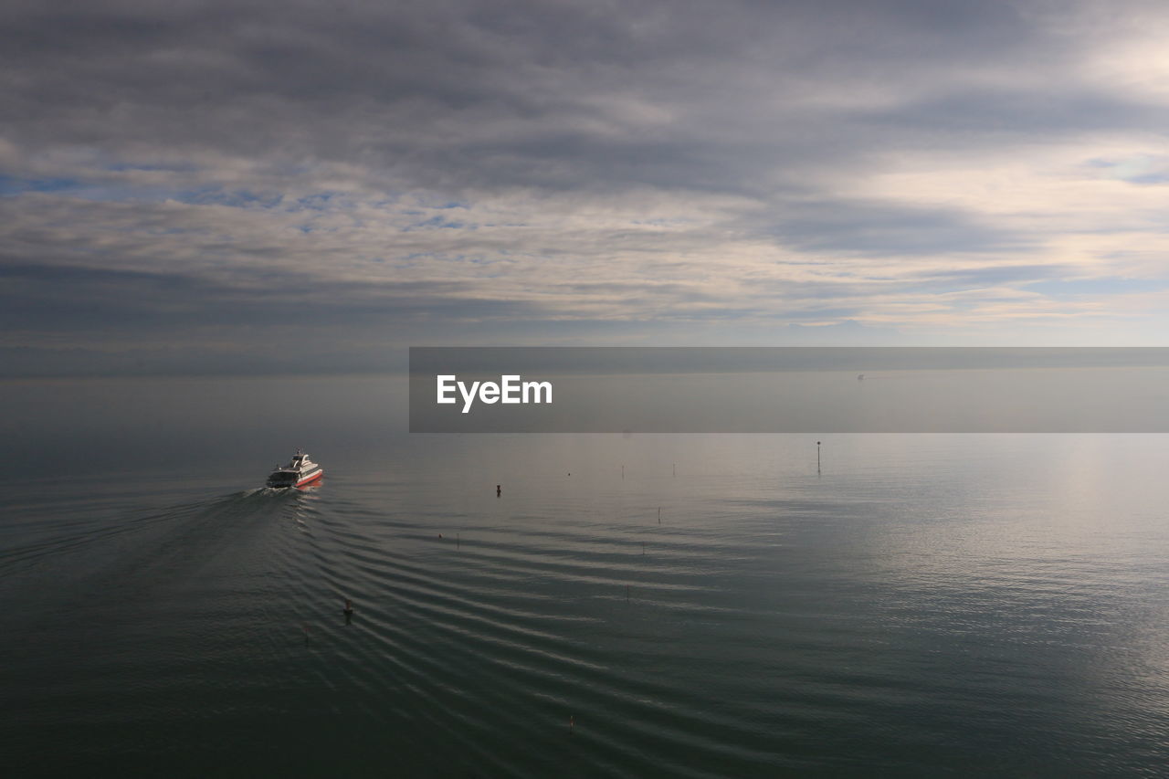 Cruise ship on sea against cloudy sky