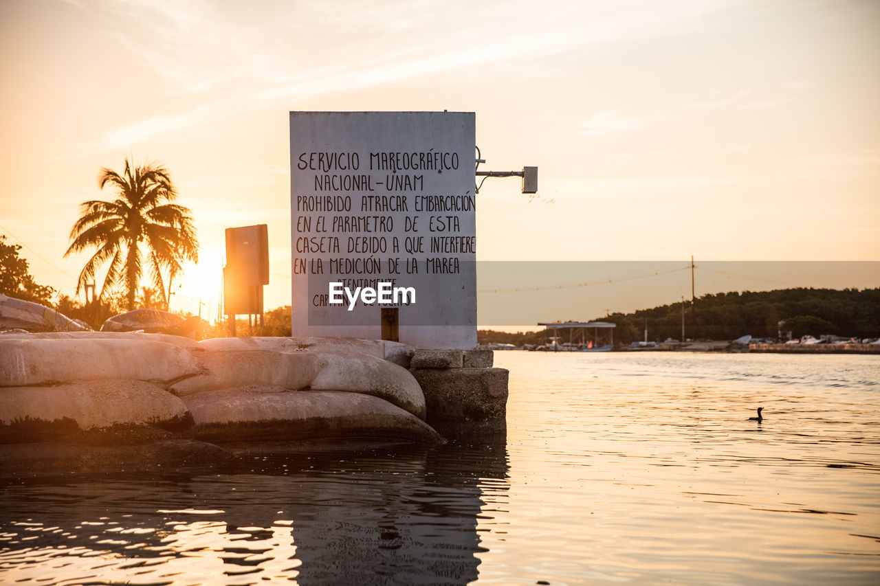 INFORMATION SIGN BY SEA AT SUNSET