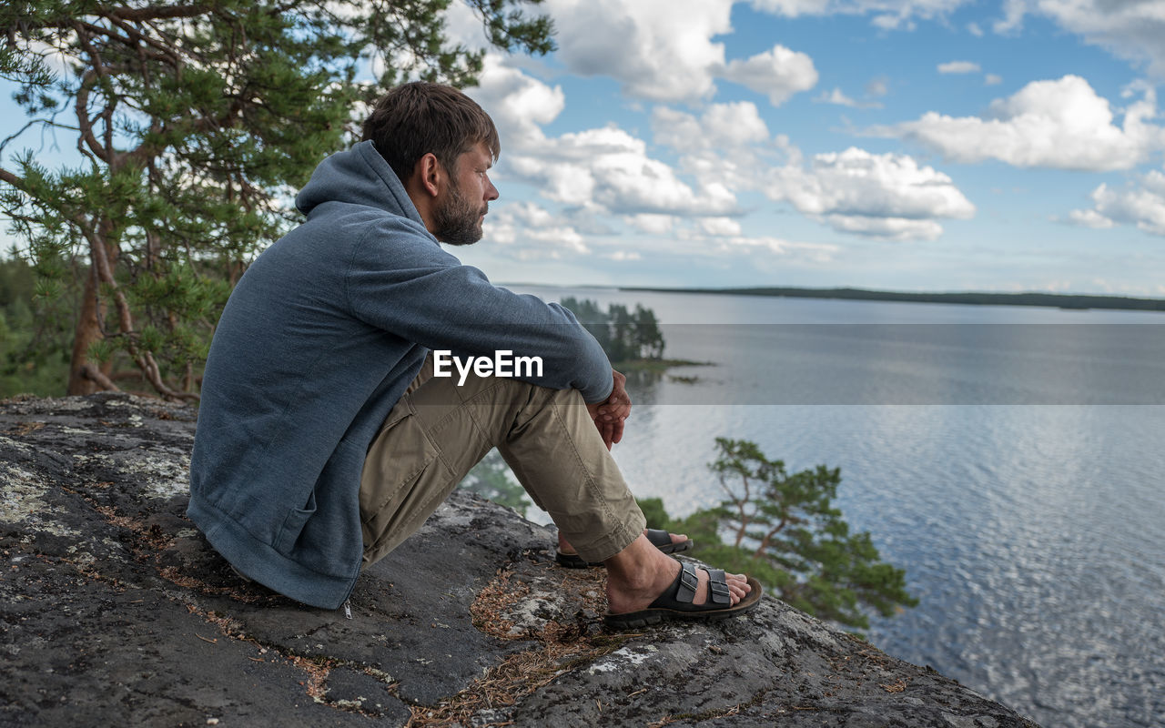 REAR VIEW OF MAN FISHING AT SEA SHORE