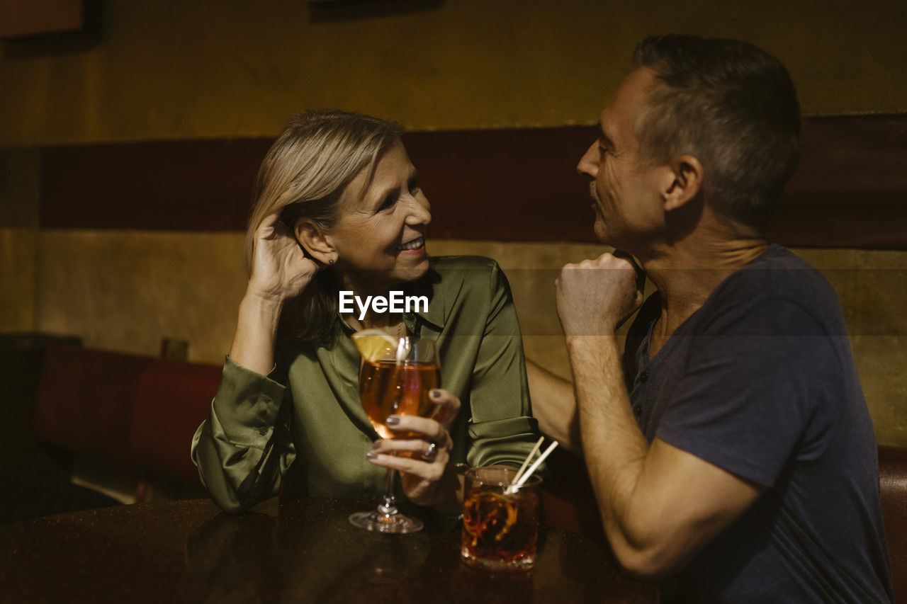 Man talking with woman holding wineglass while sitting at restaurant