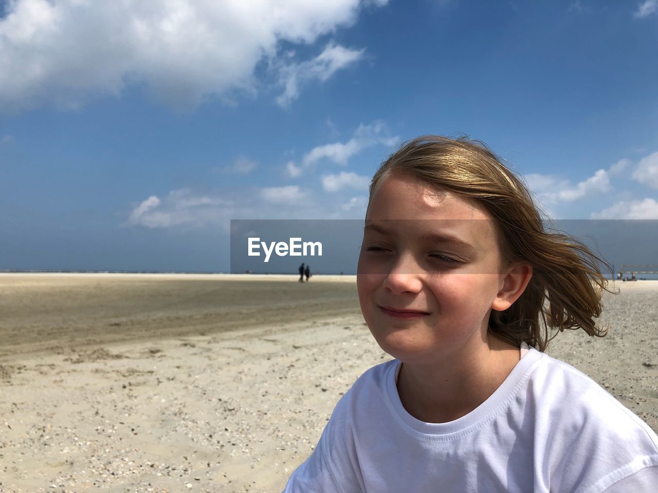 Close-up of girl with eyes closed at beach against sky