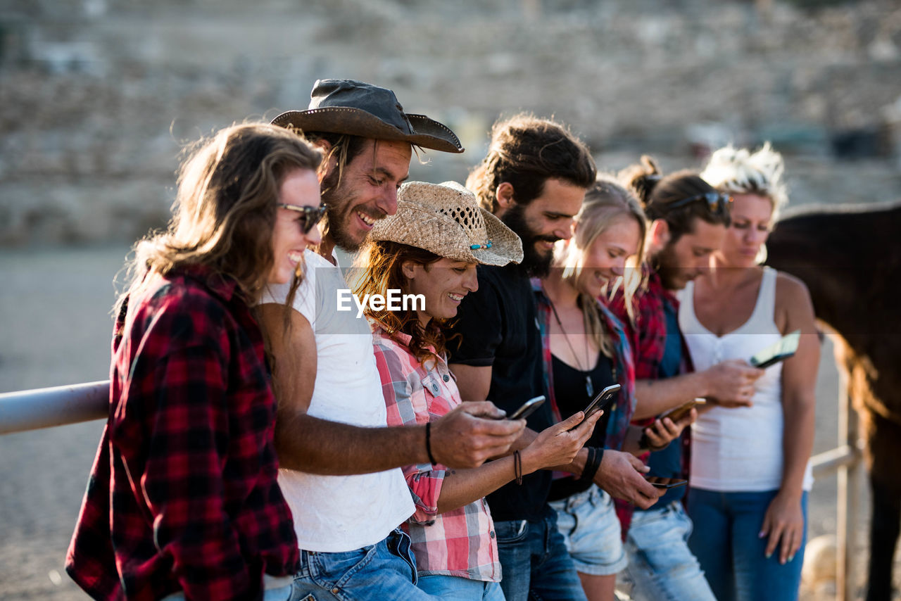 Smiling friends using phones outdoors