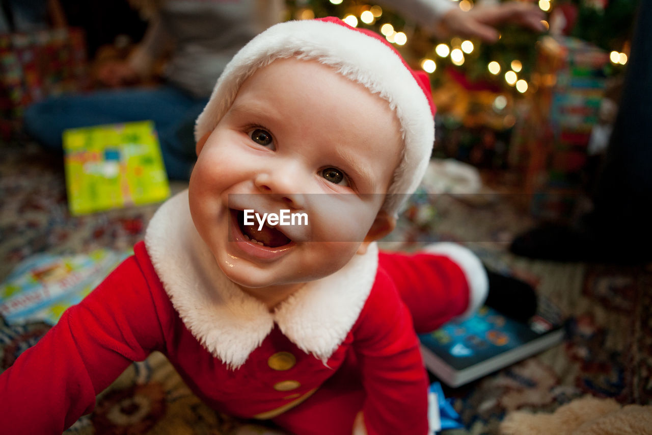 Close-up of cheerful baby boy wearing santa hat at home