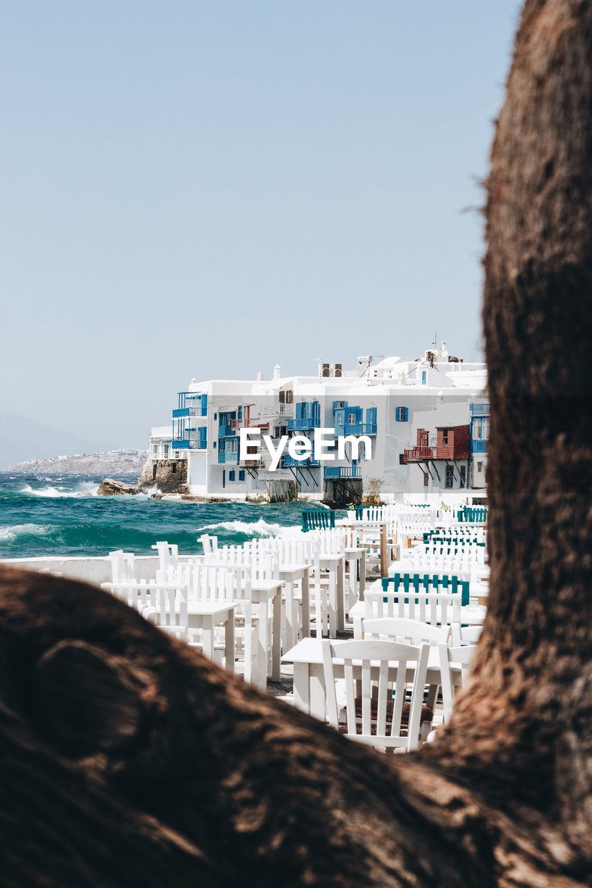 Buildings by sea against clear sky