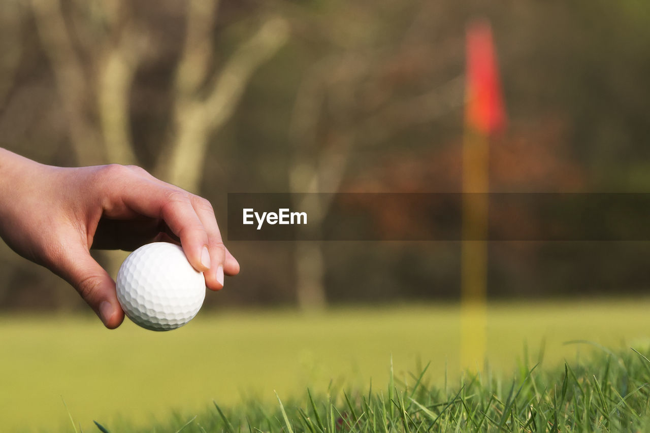 MIDSECTION OF PERSON PLAYING WITH BALL IN GRASS