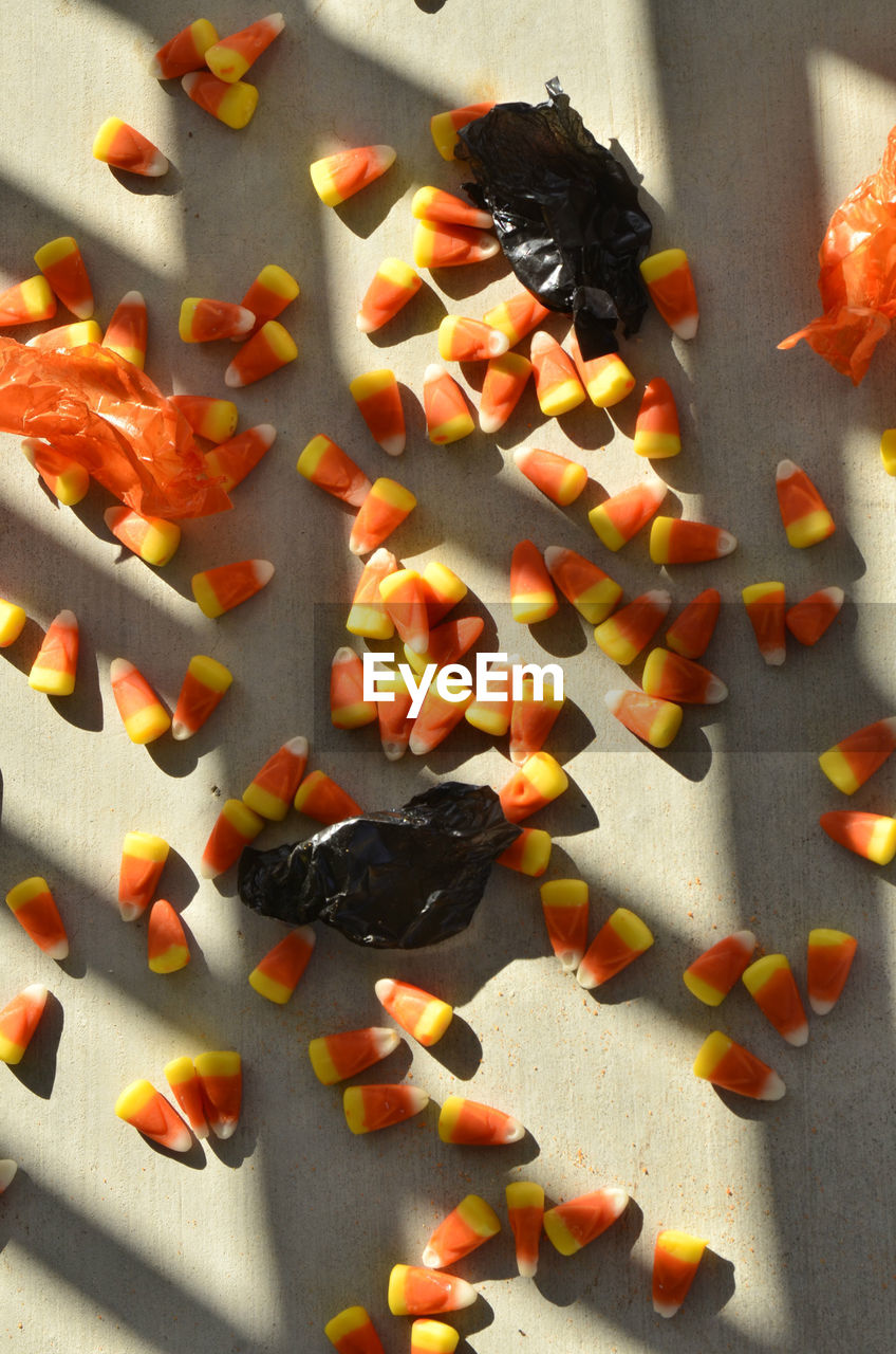 Halloween candy corn and black and orange candy wrappers in dramatic shadow and light pattern