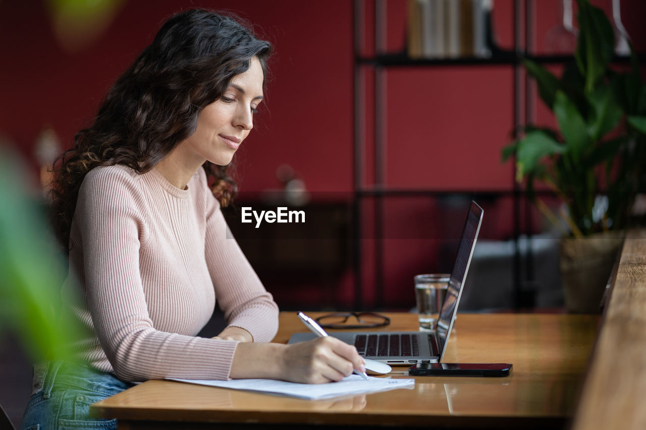 Focused girl study on laptop make notes. concentrated small business owner with pc write in notebook