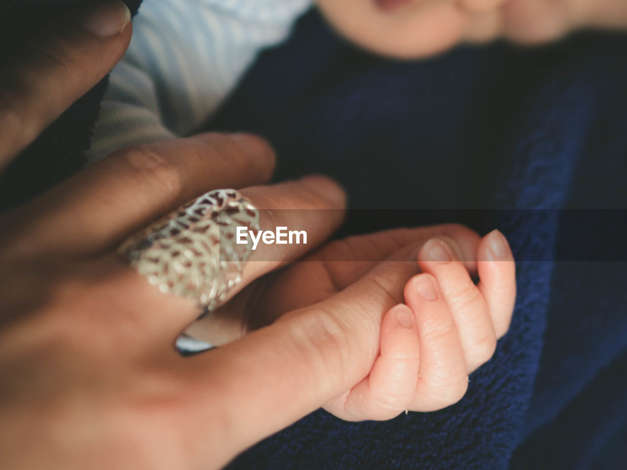 Cropped image of newborn baby holding mother hand