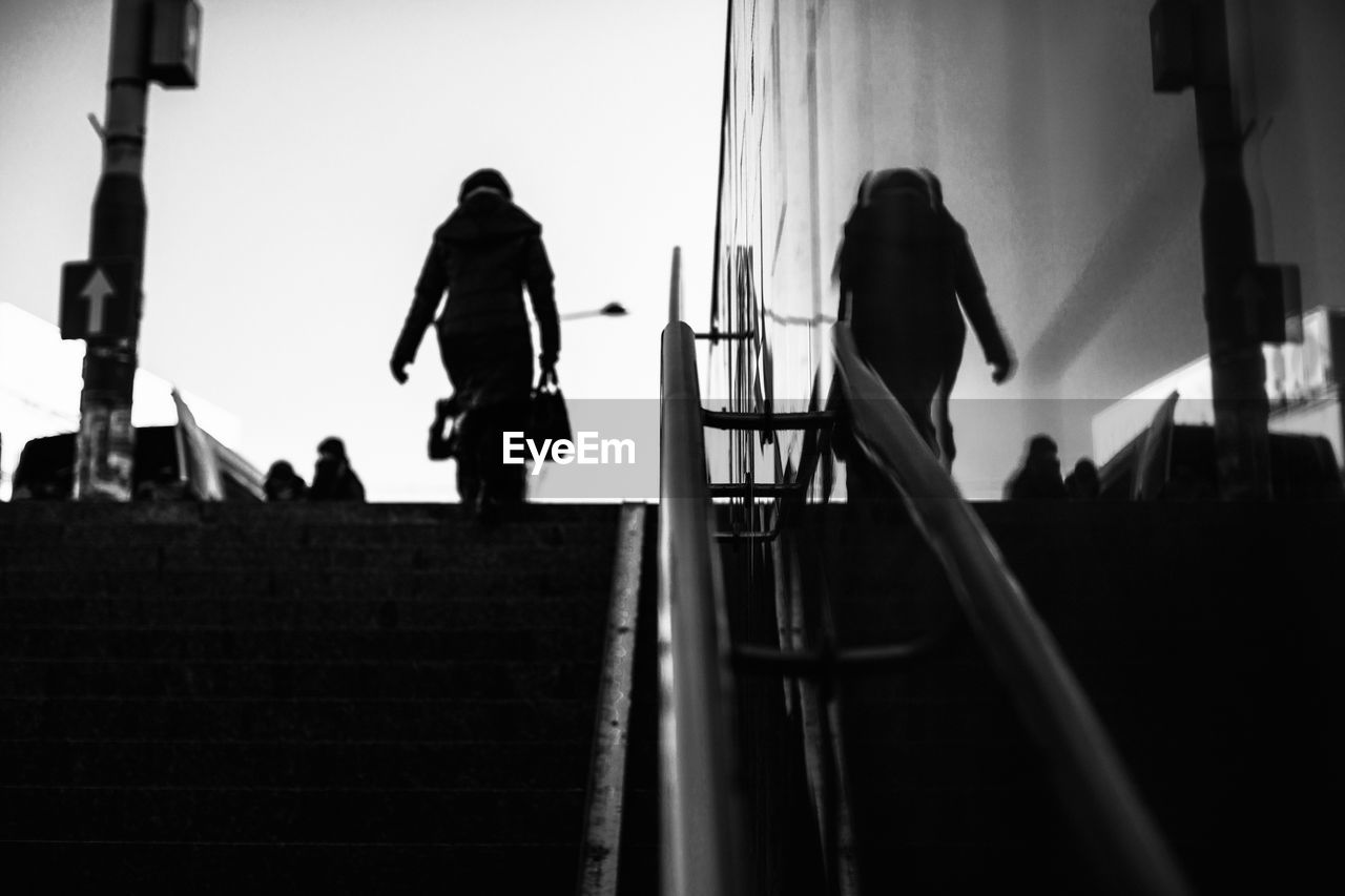 Low angle view of woman climbing stairs against sky