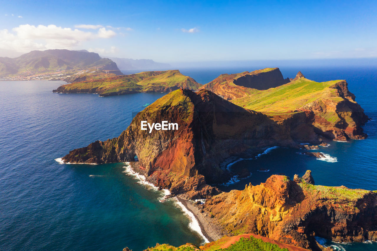 scenic view of sea by mountain against sky