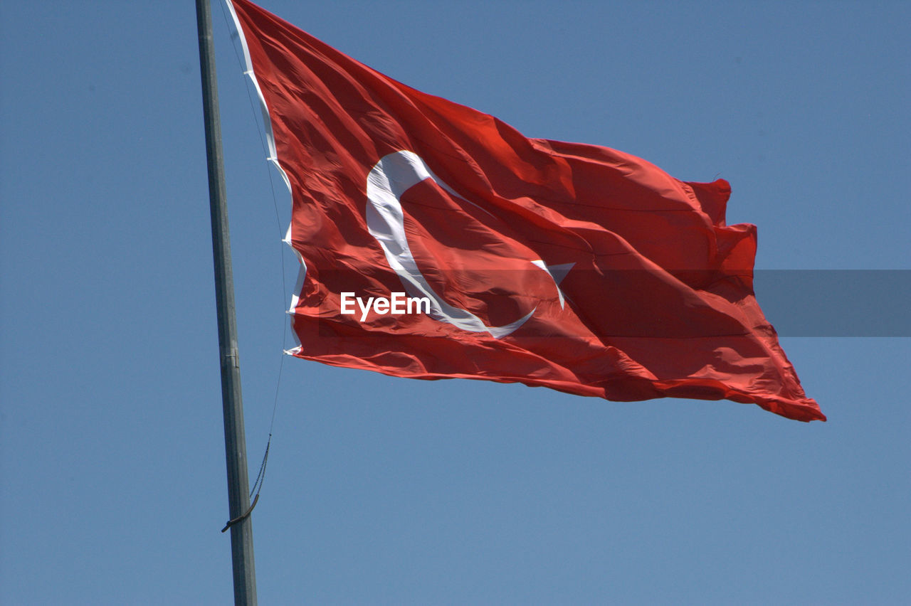 Low angle view of turkish flag against clear blue sky