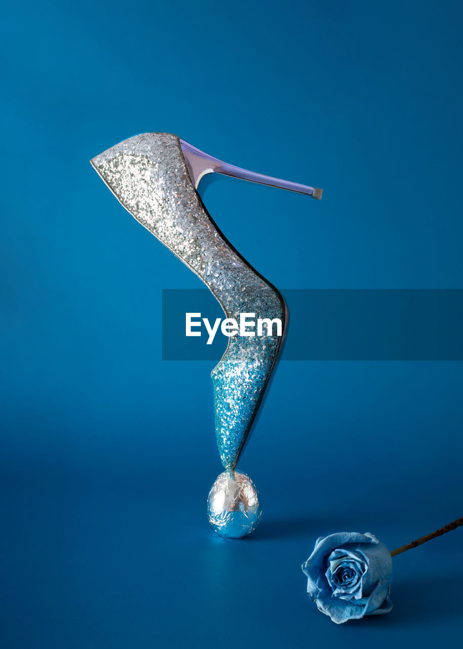 Elegant shoe made of glitter with a high heel on top standing on a silver egg. minimal concept 