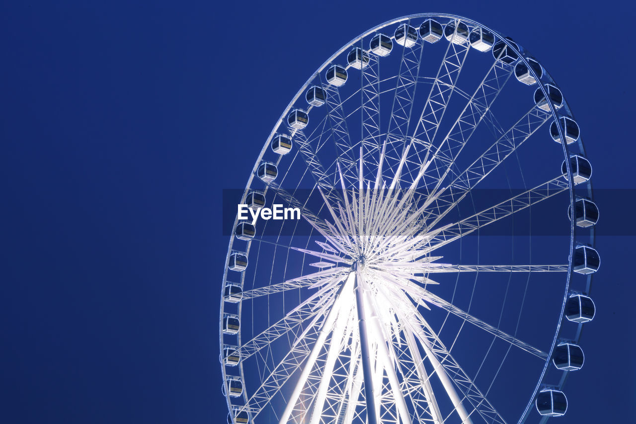 LOW ANGLE VIEW OF ILLUMINATED FERRIS WHEEL AGAINST SKY