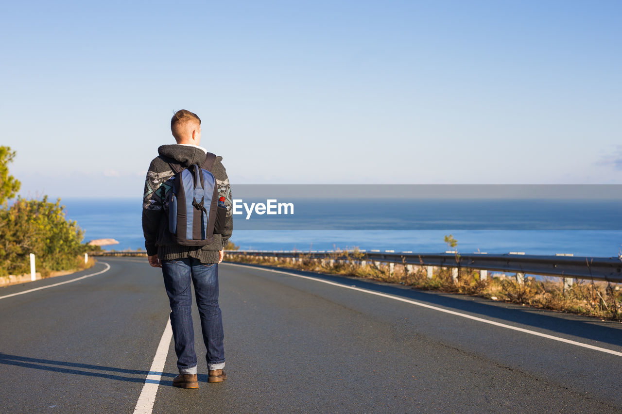 Rear view of man standing on road against sky