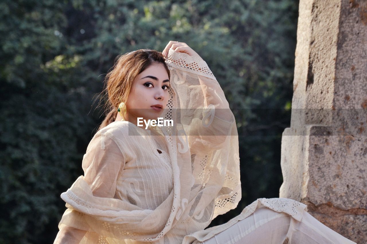 Portrait of young woman sitting against blurred background