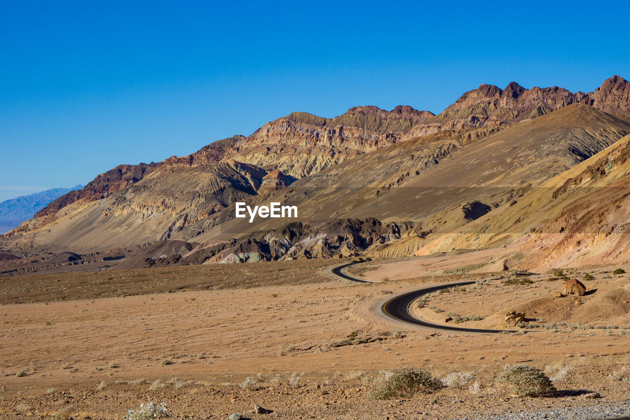 Scenic view of desert against clear blue sky