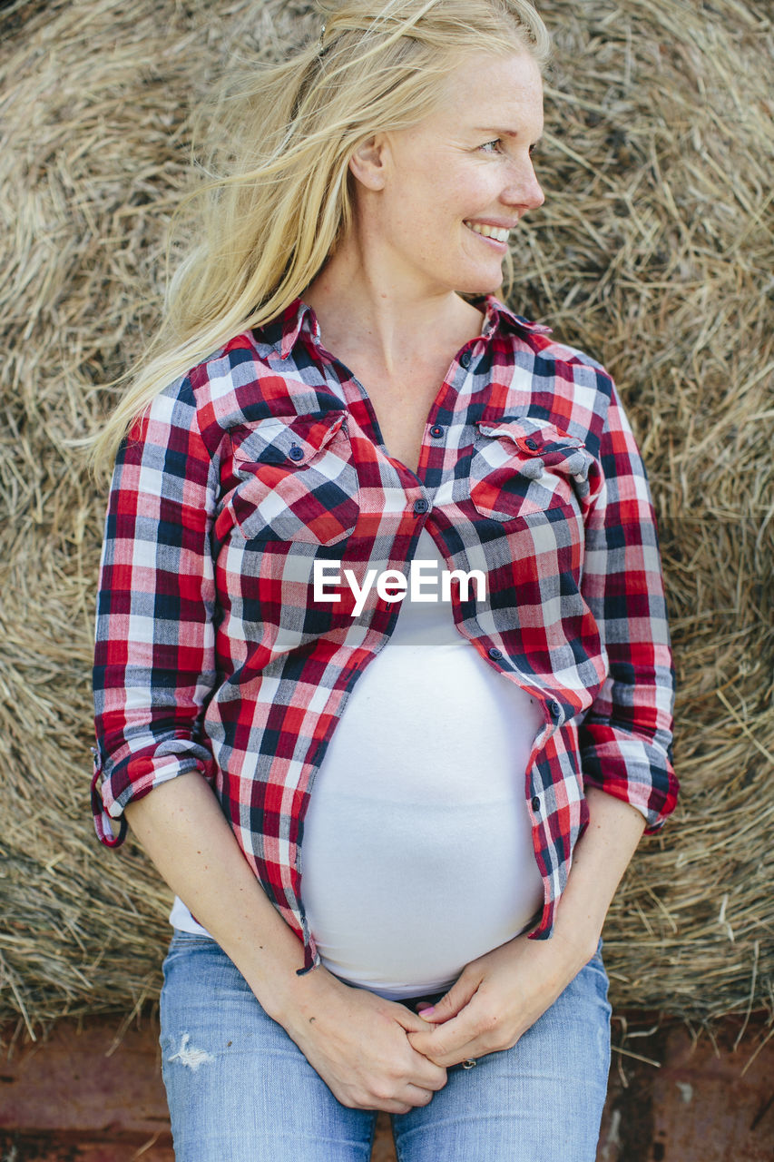 Pregnant woman leaning on haybale