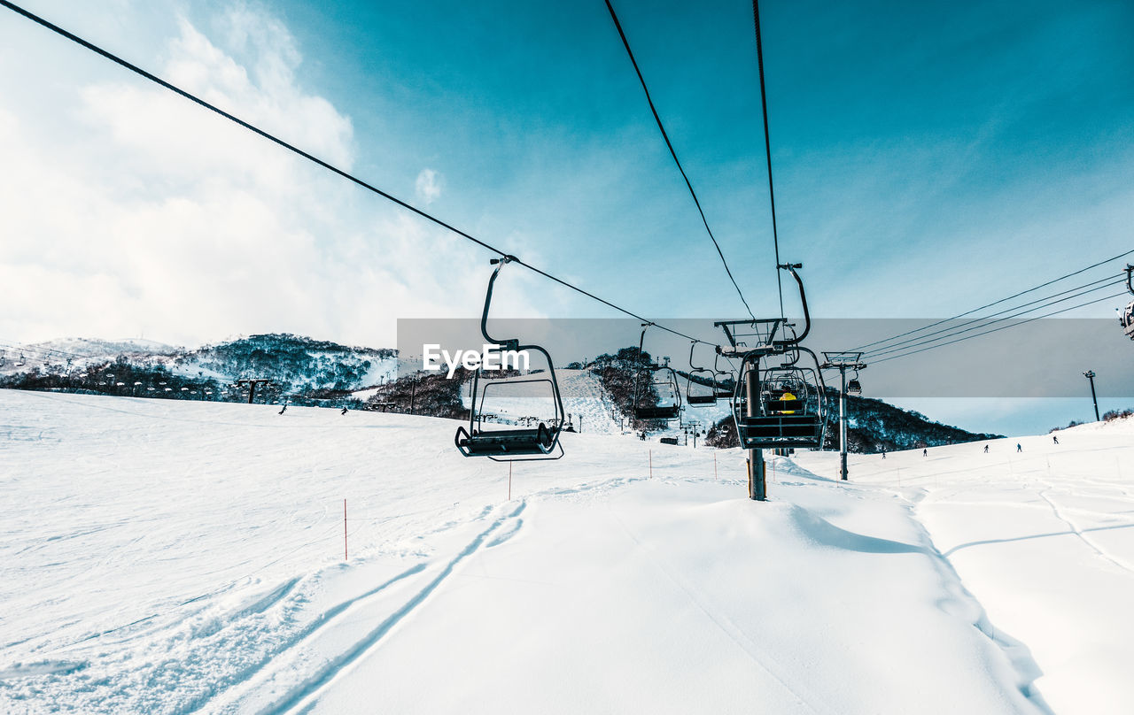 Overhead cable cars against sky during winter