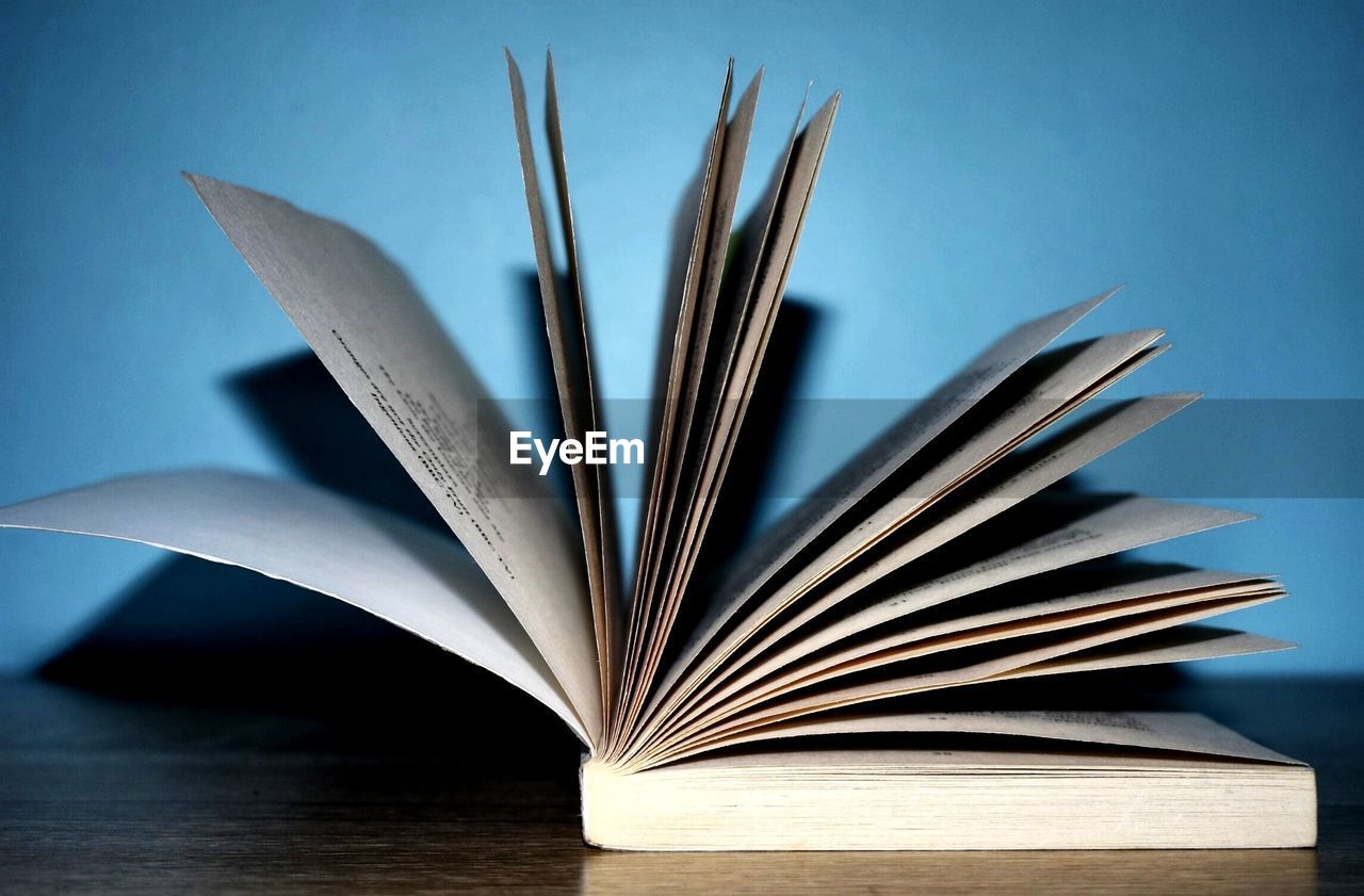 Close-up of open book on table against blue background