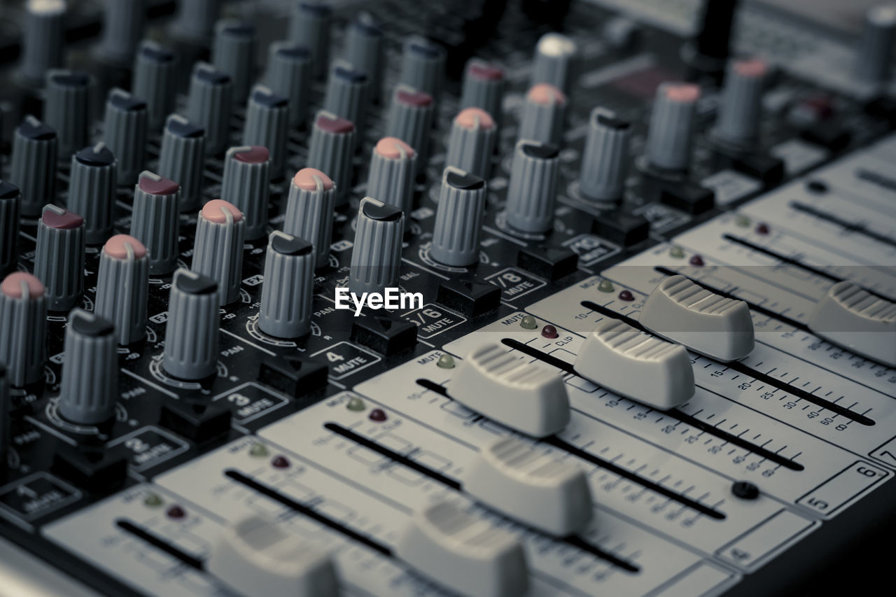 Closeup and detail of audio mixing console with faders and knobs. used for audio production