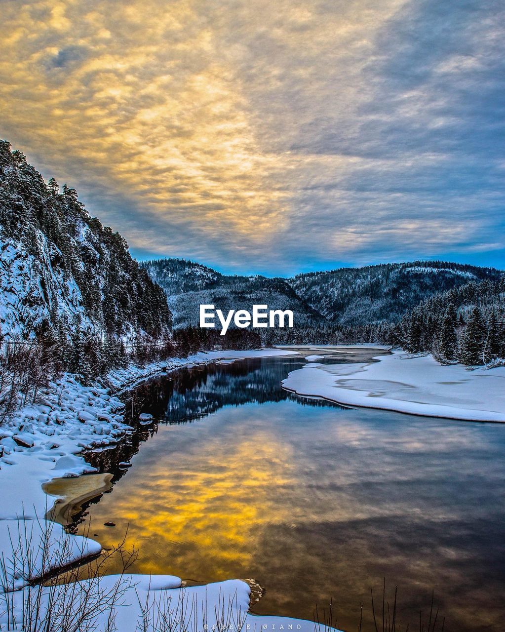 Scenic view of sea by mountains against cloudy sky