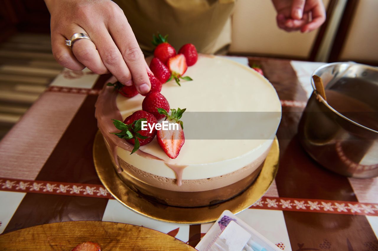 cropped hand of woman with cake on table