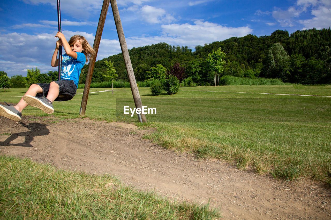 Boy sitting on zip line at playground