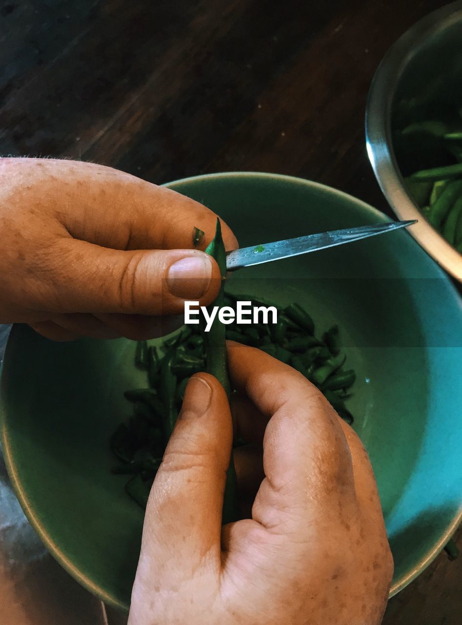 Cropped hands cutting green bean