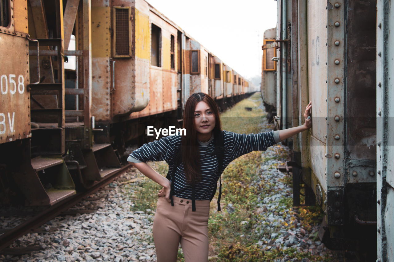 Young woman looking away while standing by train