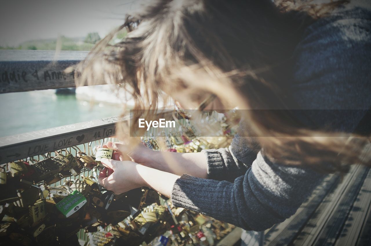 High angle view of woman locking padlock at pont des arts bridge