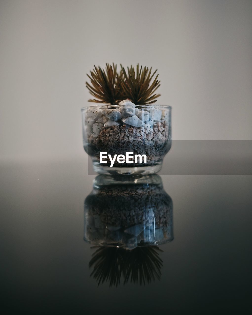 CLOSE-UP OF GLASS CONTAINER WITH REFLECTION ON WATER