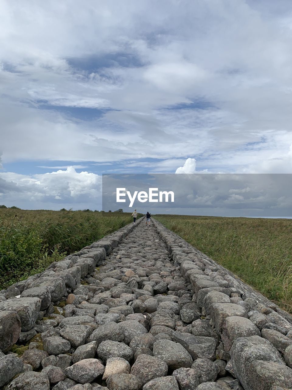 DIRT ROAD ON FIELD AGAINST SKY