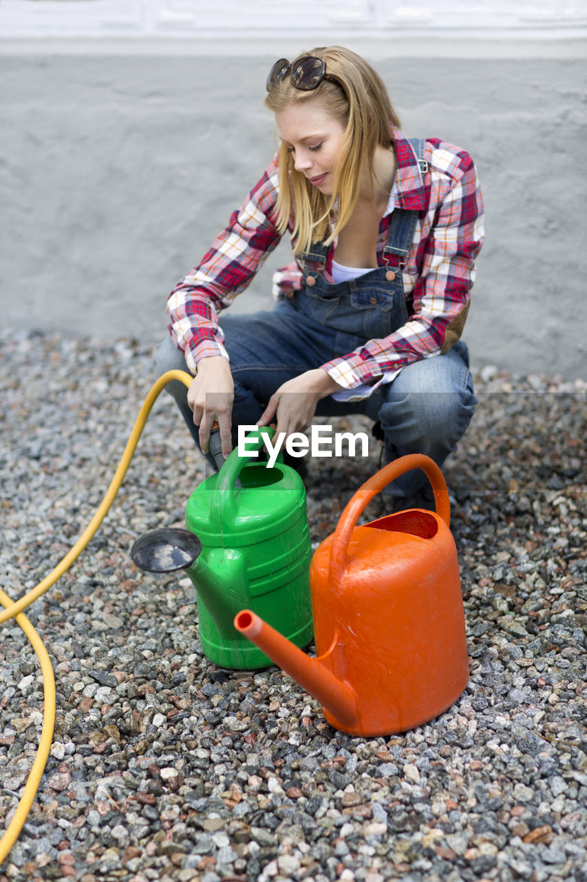 Young woman filling watering cans, stockholm, sweden