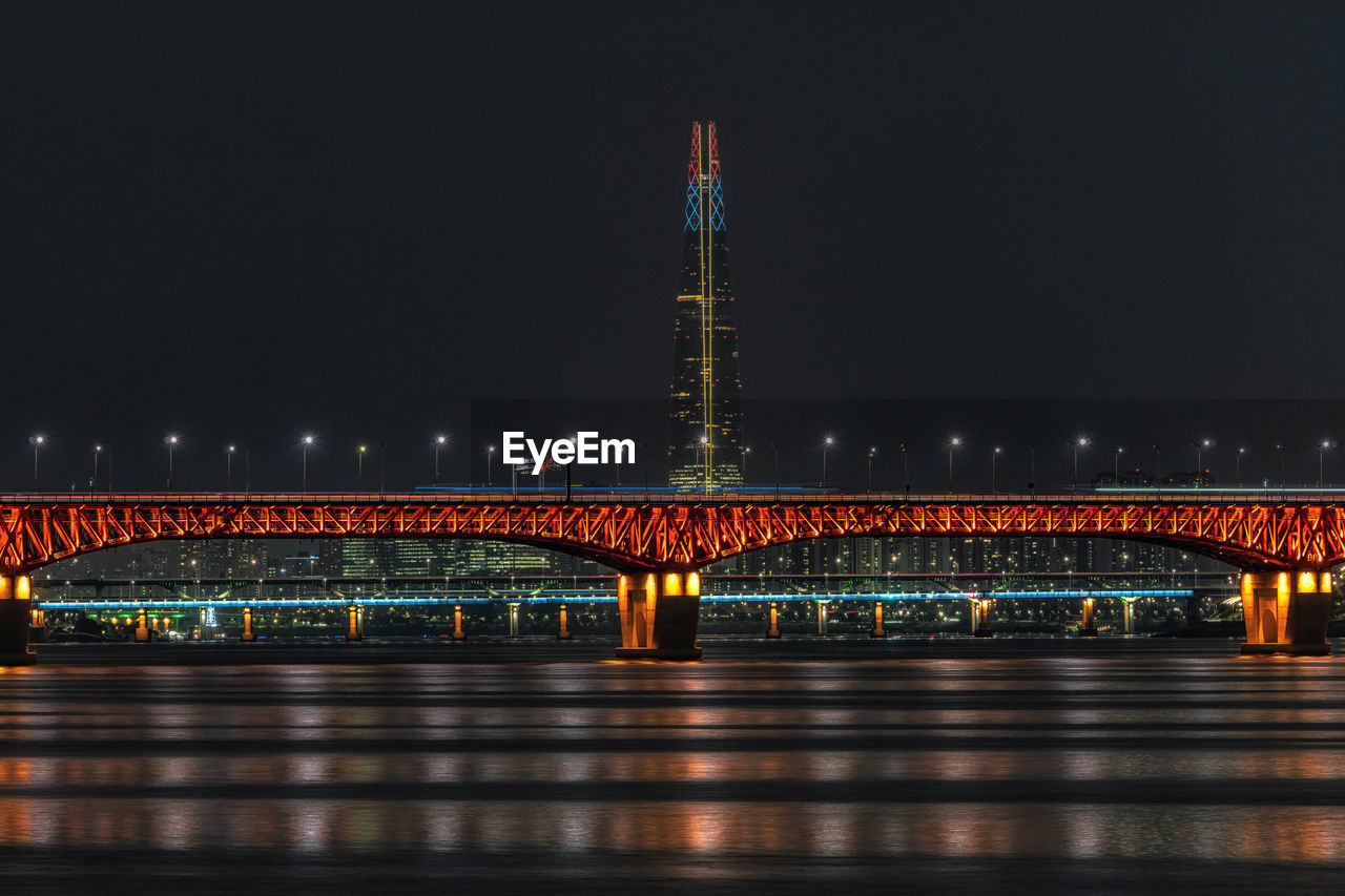 Illuminated bridge over river at night