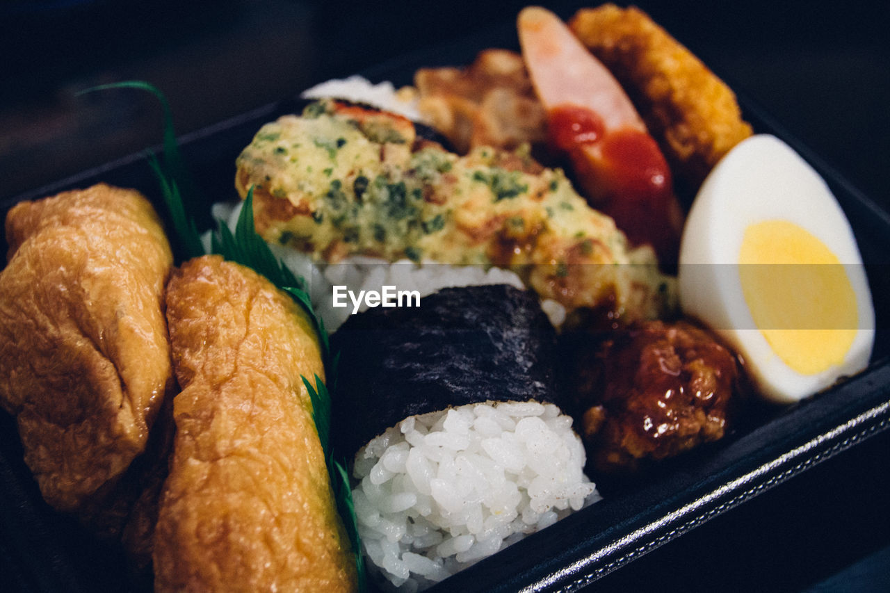 Close-up of sushi with meat and egg in container