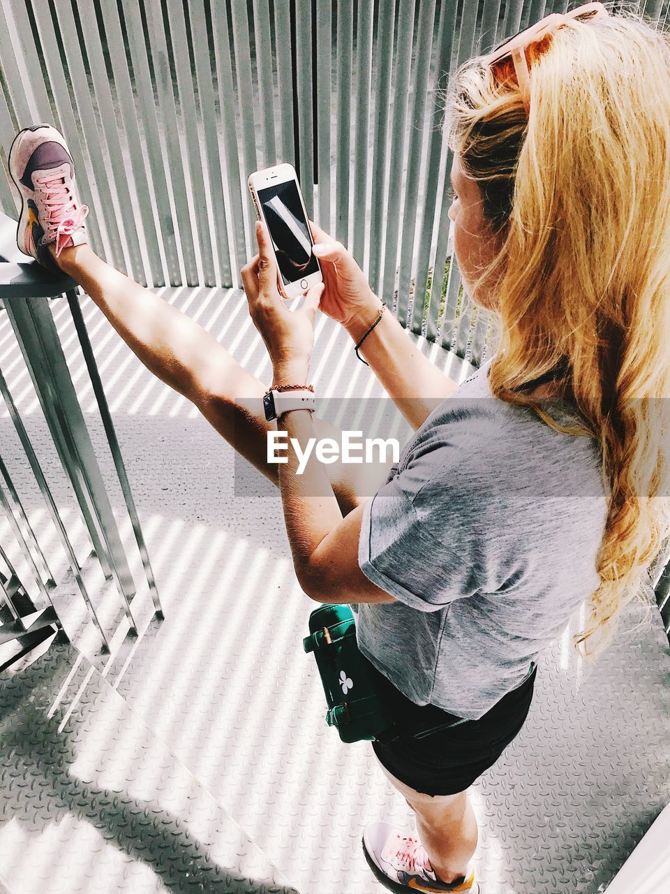 WOMAN HOLDING MOBILE PHONE WHILE USING SMART LAPTOP