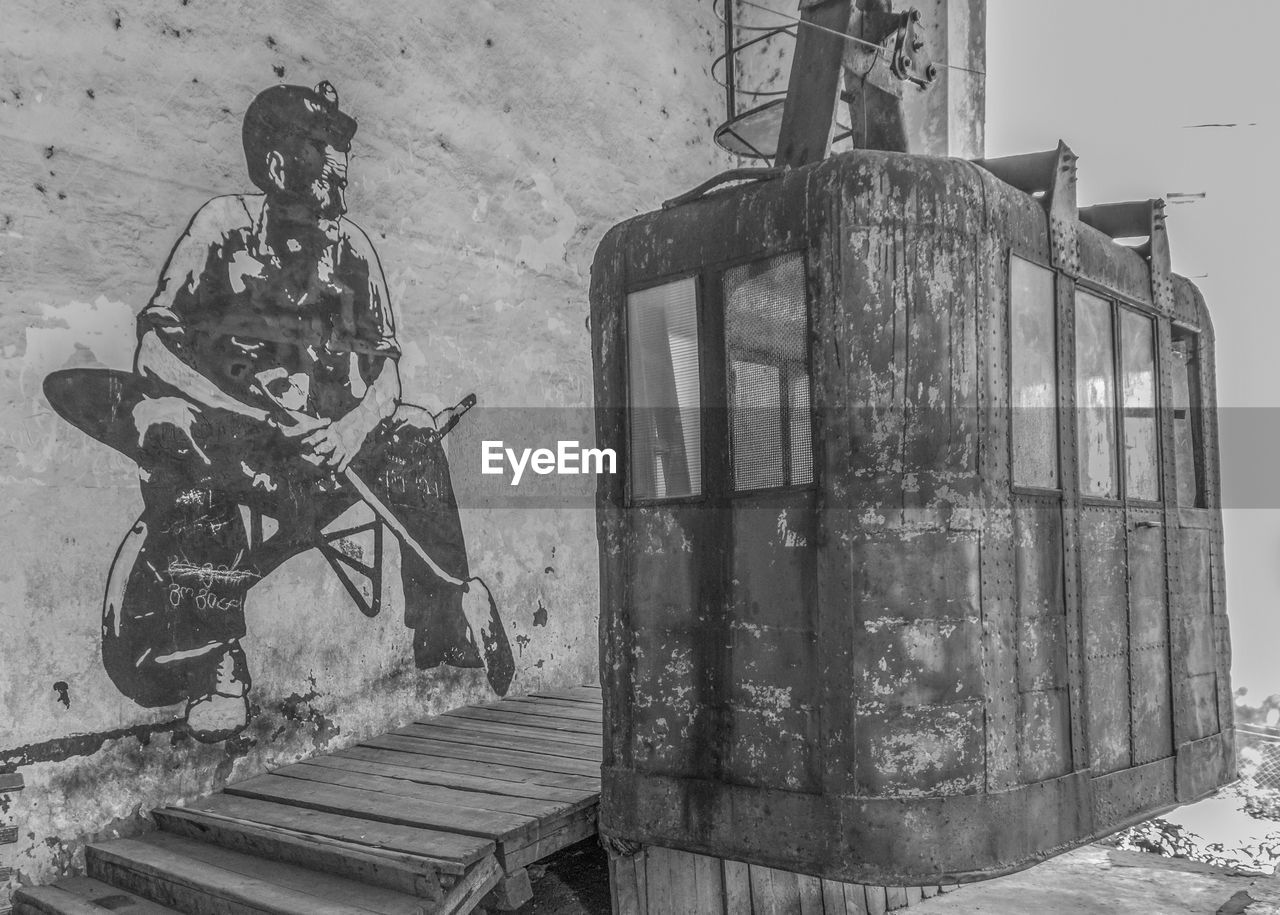 VIEW OF OLD MAN SITTING IN ABANDONED WALL