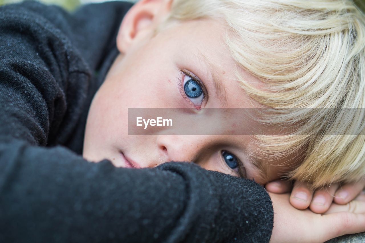 Close-up portrait of young boy lying down