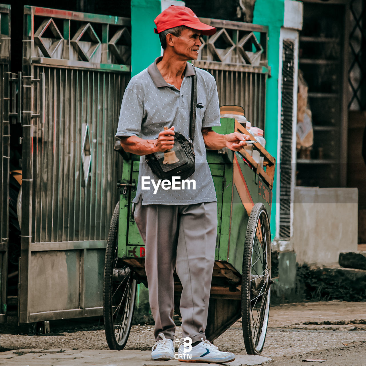 FULL LENGTH OF MAN HOLDING BICYCLE WHILE STANDING ON CART