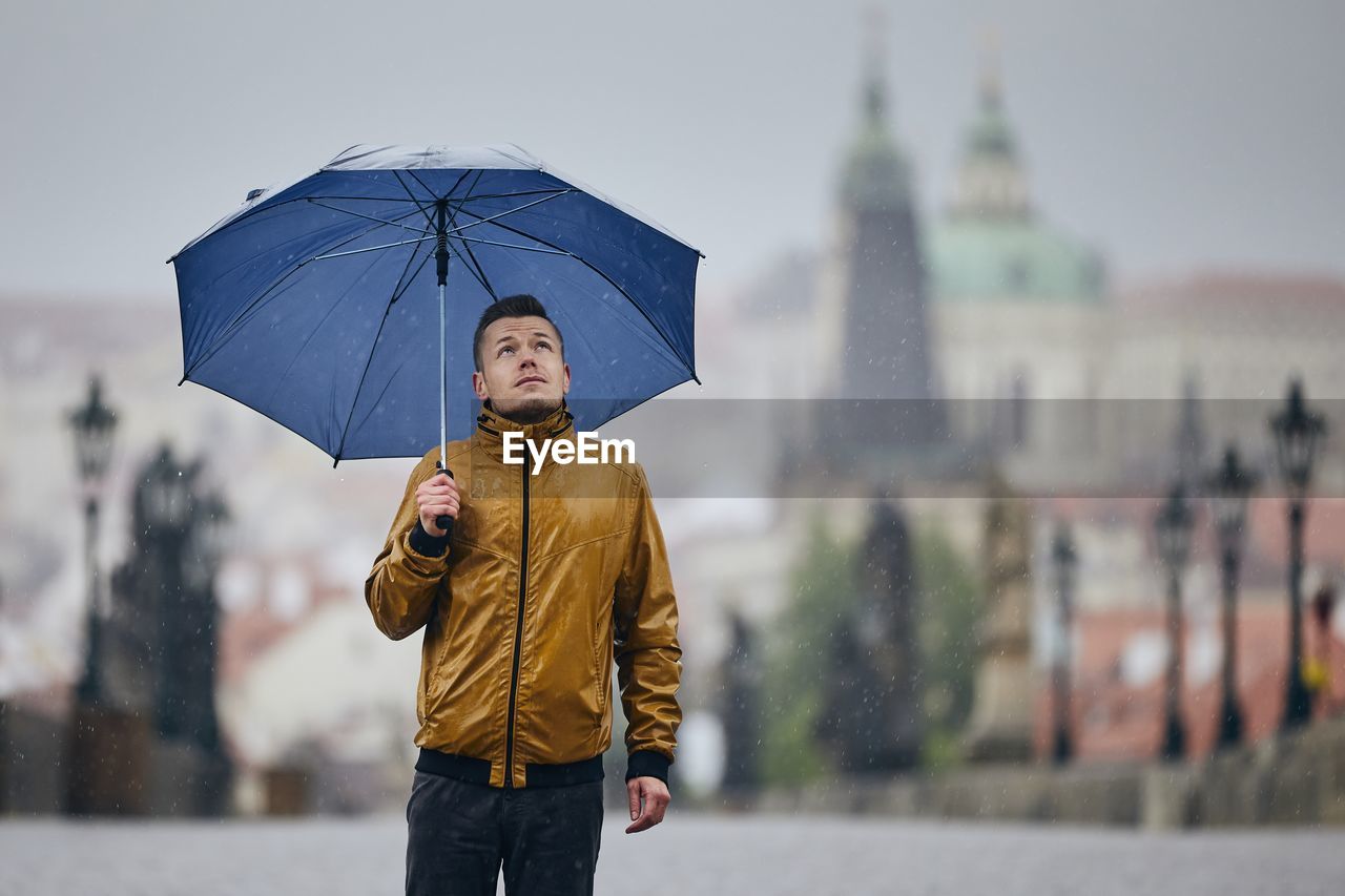 Man with umbrella standing in city during rainy season