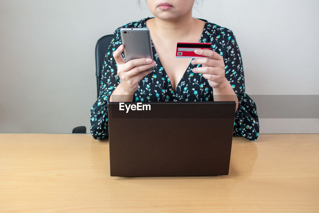 Woman holding credit card with laptop and smartphone using banking service paying shopping online 