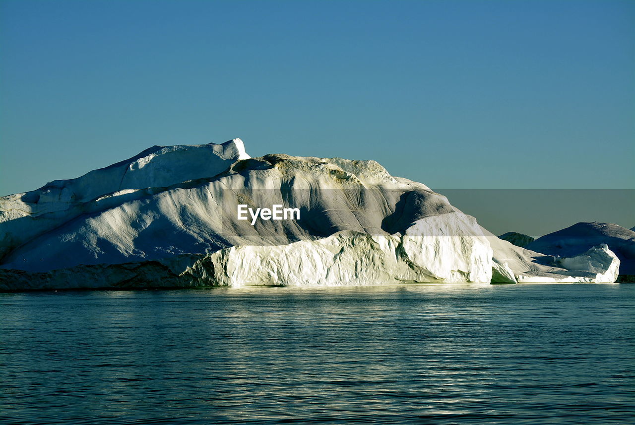 View of majestic iceberg in sea against sky