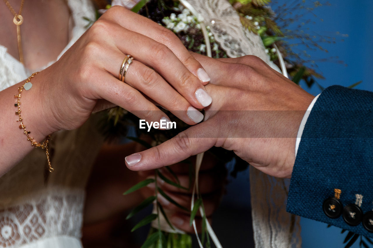Midsection of bride holding groom finger