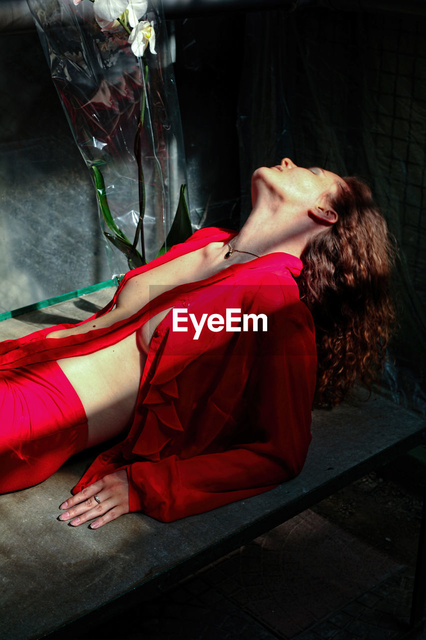 MIDSECTION OF WOMAN LYING ON RED FLOOR